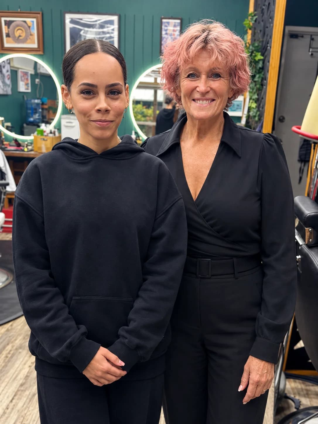 Judith and Caroline, barbers at Bear Cave Barbershop, standing together in the shop